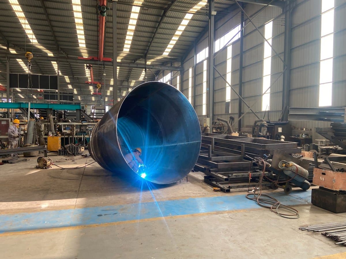 Welder fabricating a large steel drum shell in the Kingpin Engineering workshop