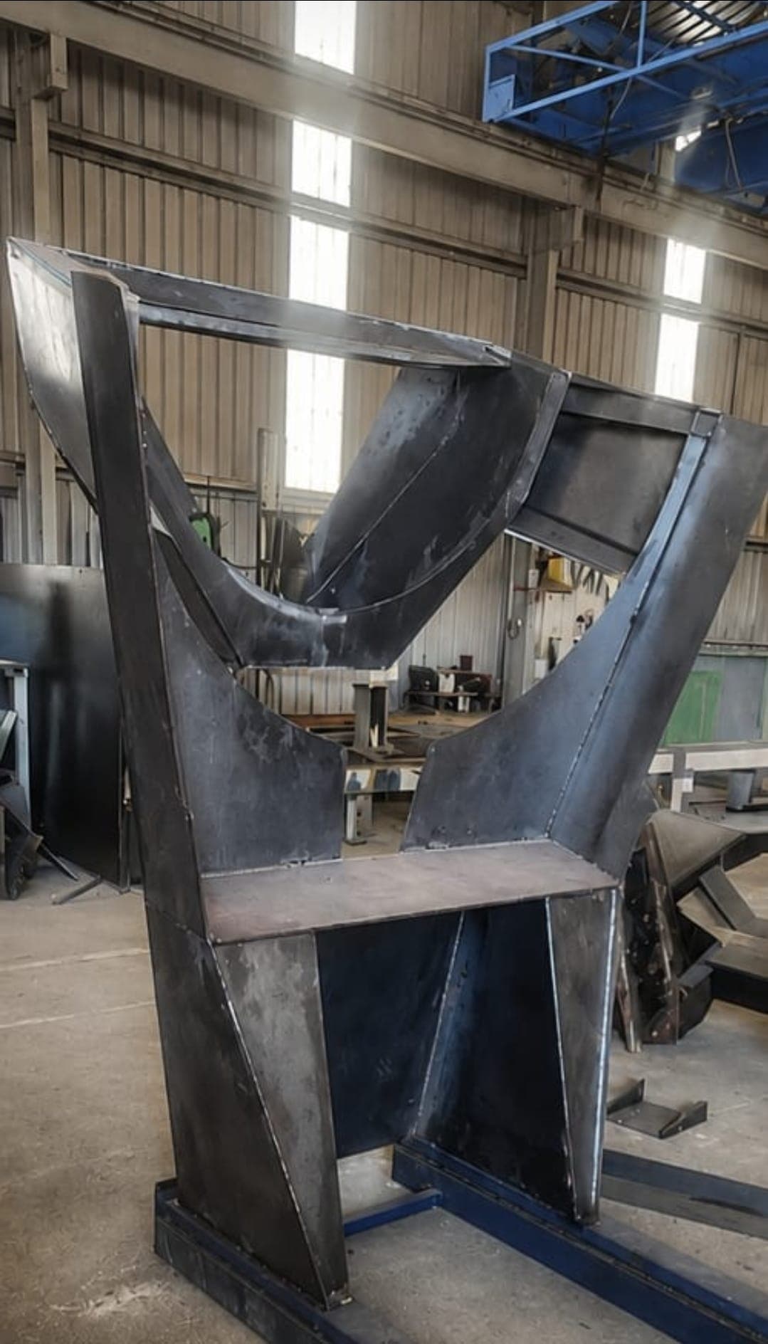 Heavy steel hopper chute weldment under fabrication in the workshop.