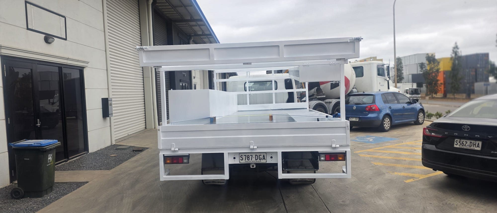 Rear view of a custom white tray build with drop sides and integrated tail-lights.