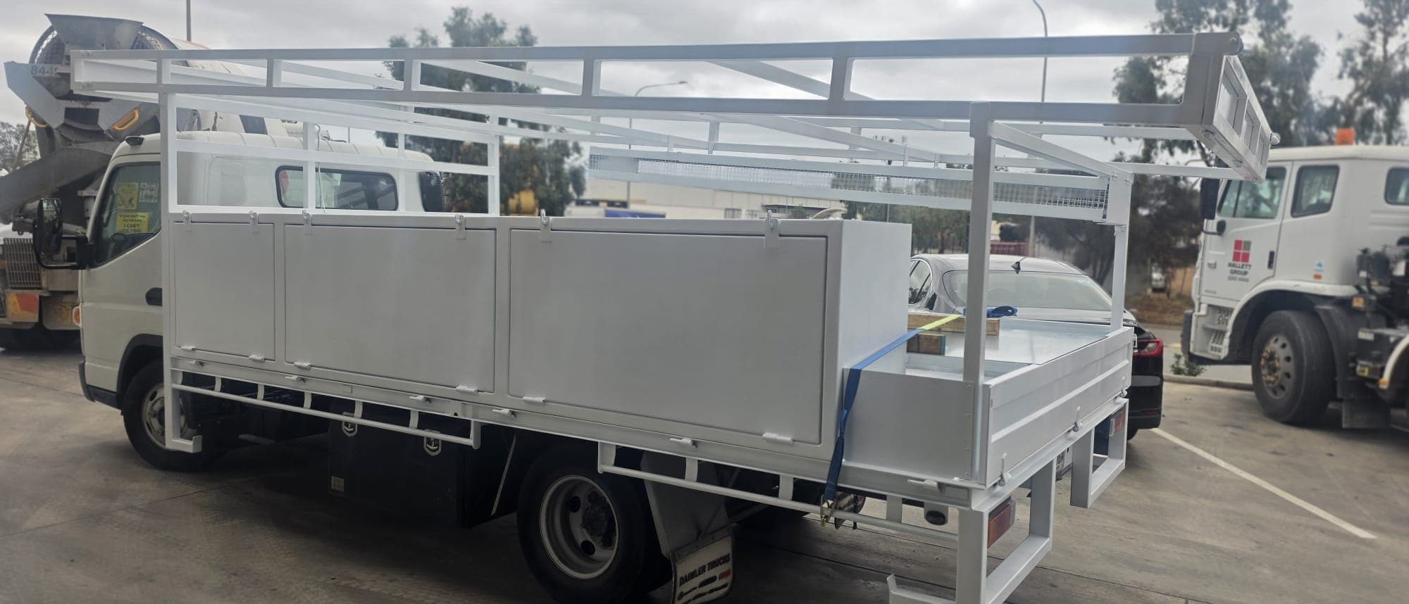 Side view of a white custom tray with enclosed toolboxes and mesh ladder rack shelf.