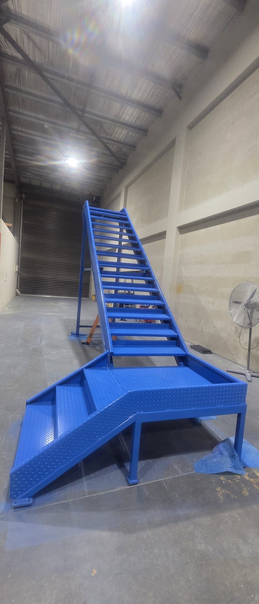 Freshly painted blue steel access staircase standing in the Kingpin workshop.