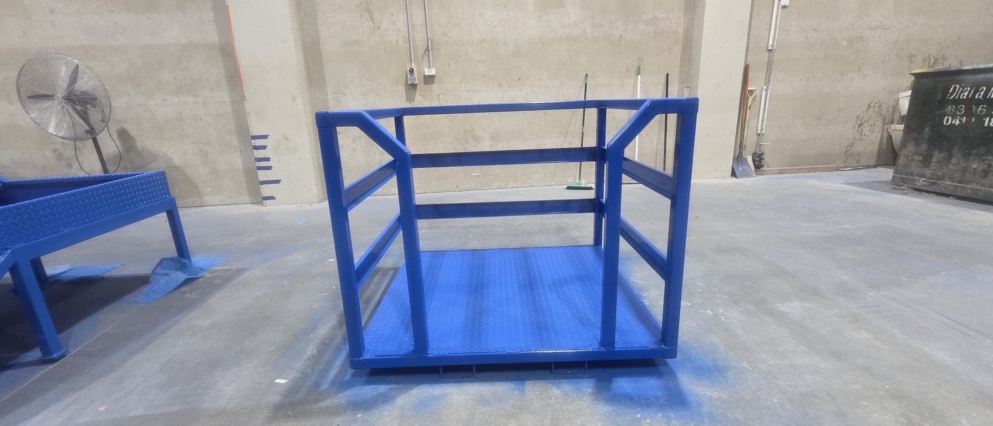 Blue forklift safety cage with checker-plate floor fabricated by Kingpin Engineering.