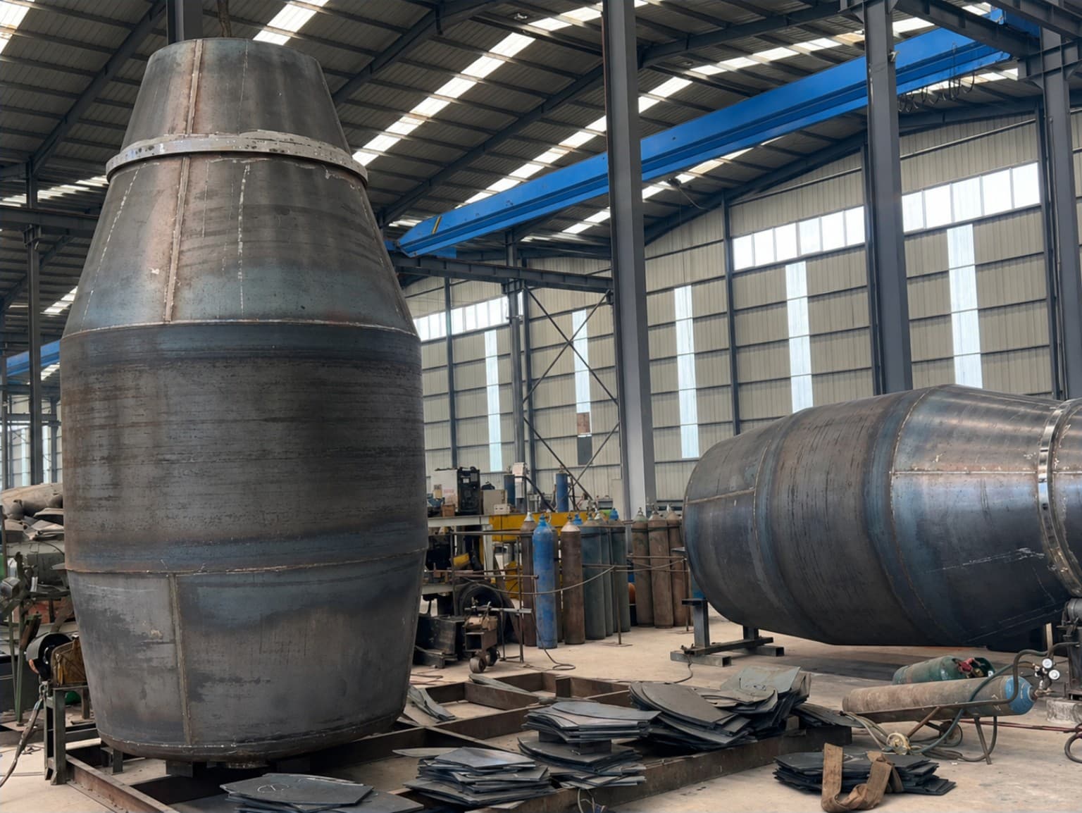 Two large concrete agitator drums under fabrication on the workshop floor.