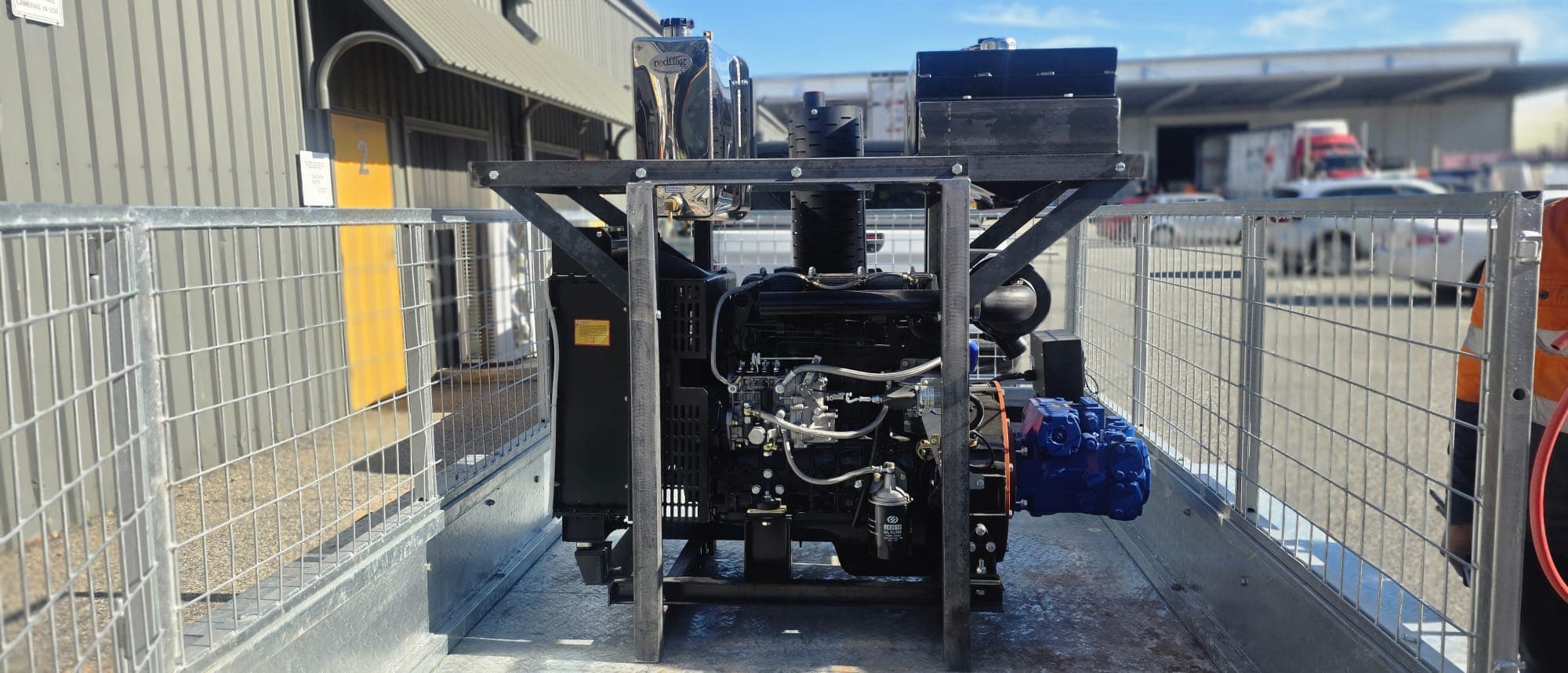 Diesel engine and hydraulic pump power pack built into a caged trailer skid.