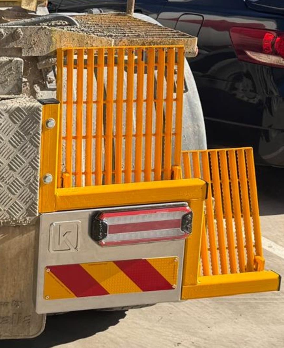 Close-up of orange safety guard grates and stainless tail-light panel on a truck rear.